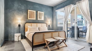 A modern bedroom with a bed, bedside lamps, a small table, and a view of the outside.