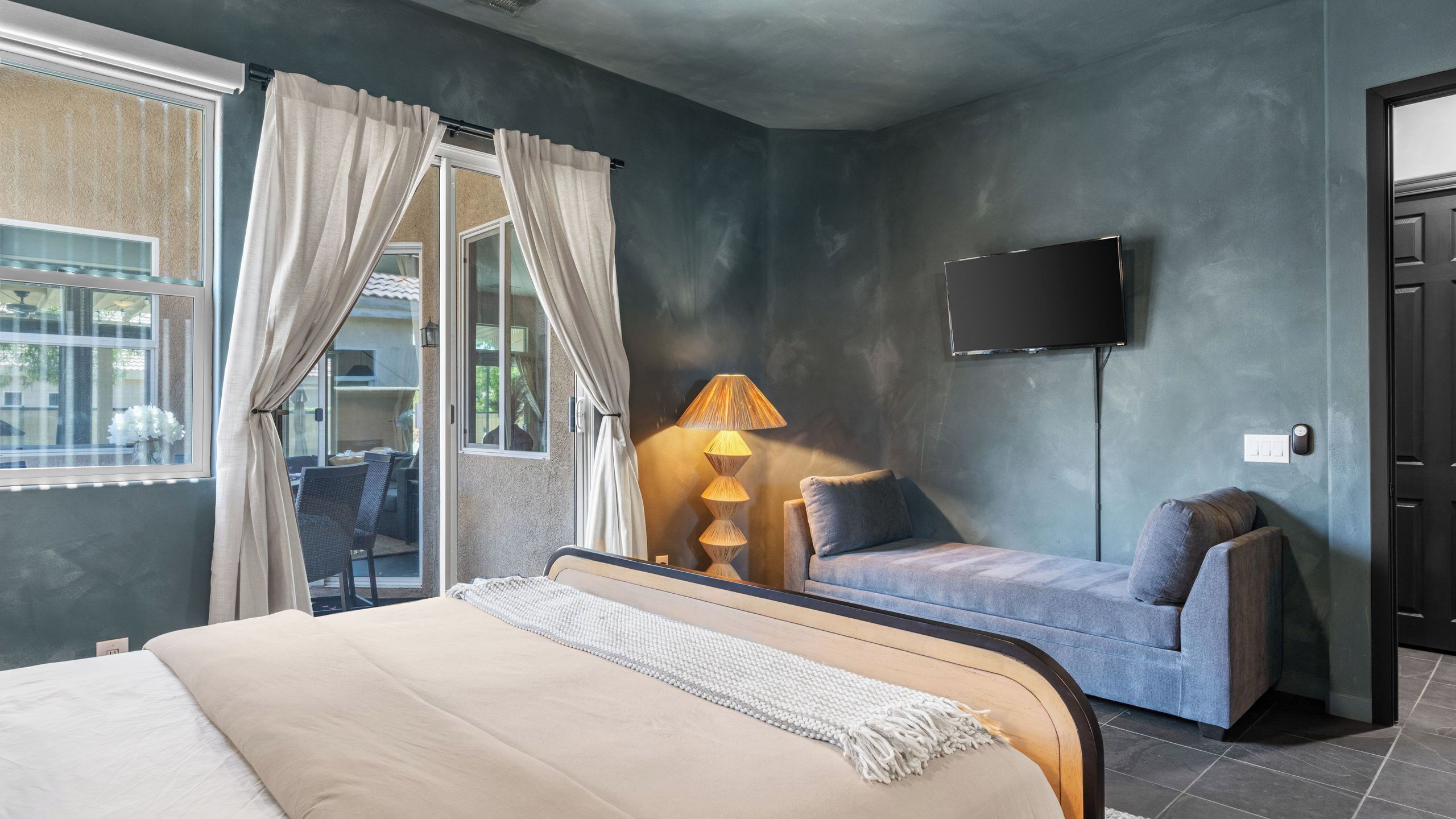 Quarto com cama, sofá, televisão e luminária.