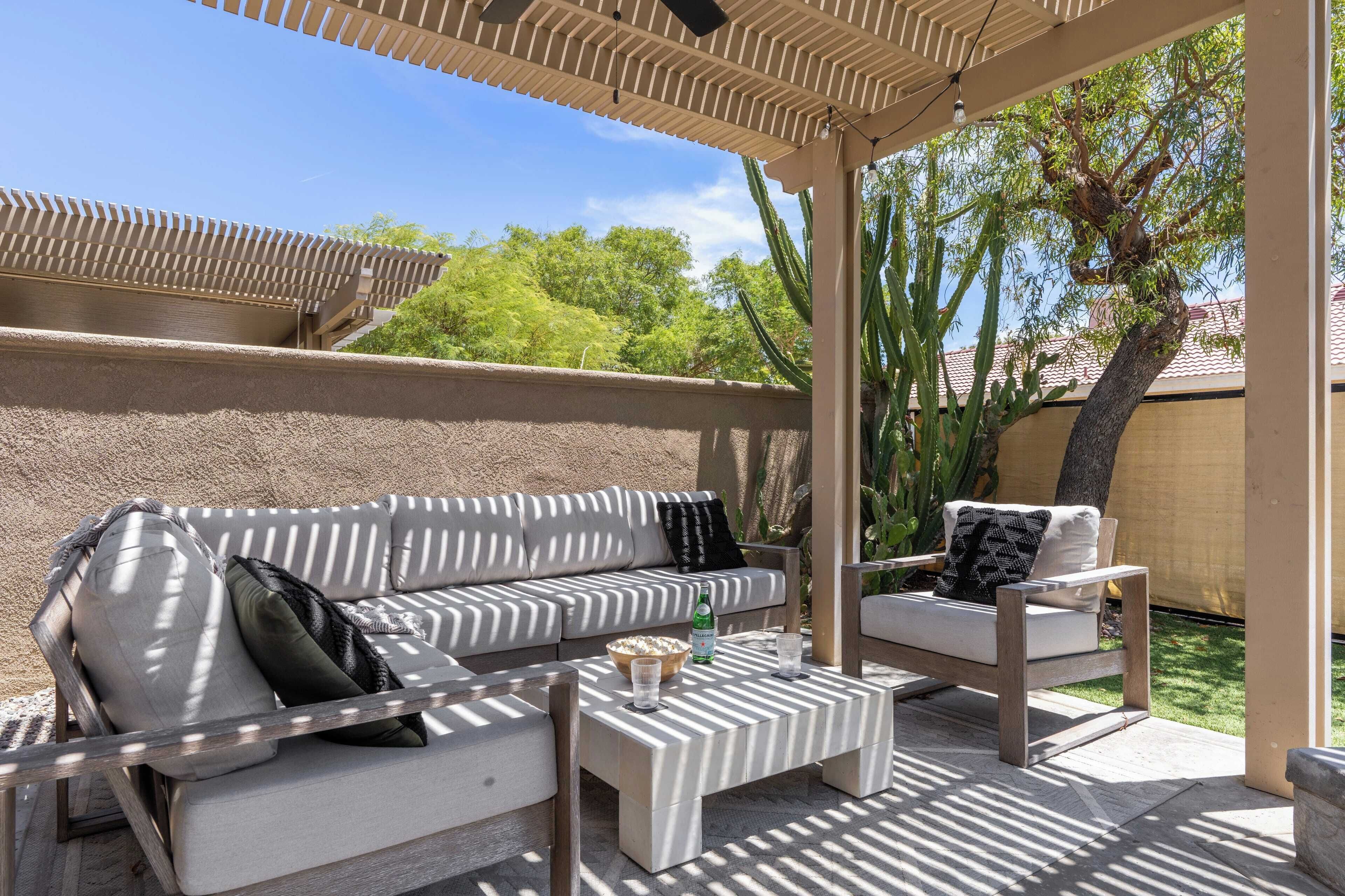 An outdoor patio with a sofa, two chairs, and a coffee table.