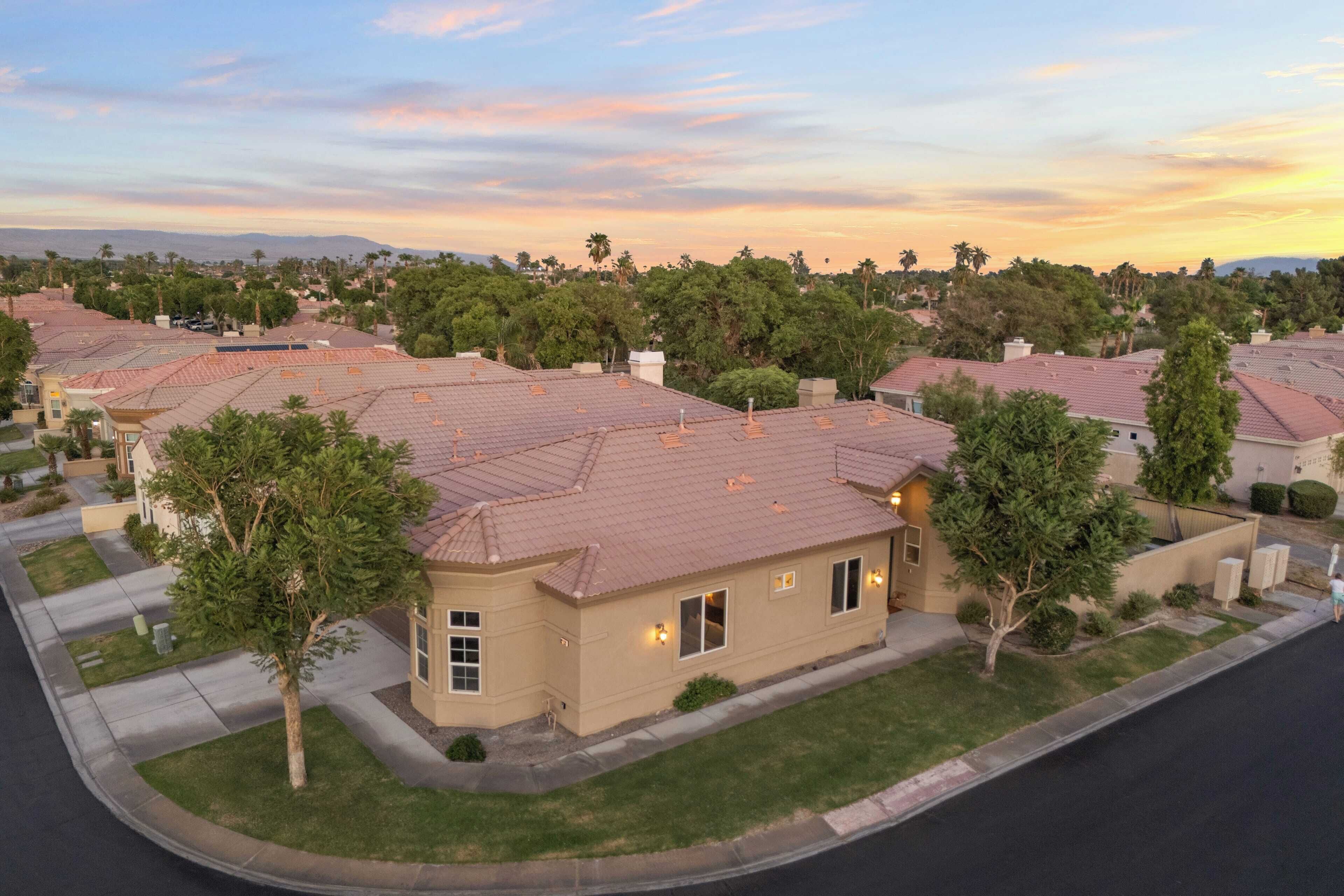 A residential neighborhood with houses featuring red-tiled roofs and well-maintained lawns.
