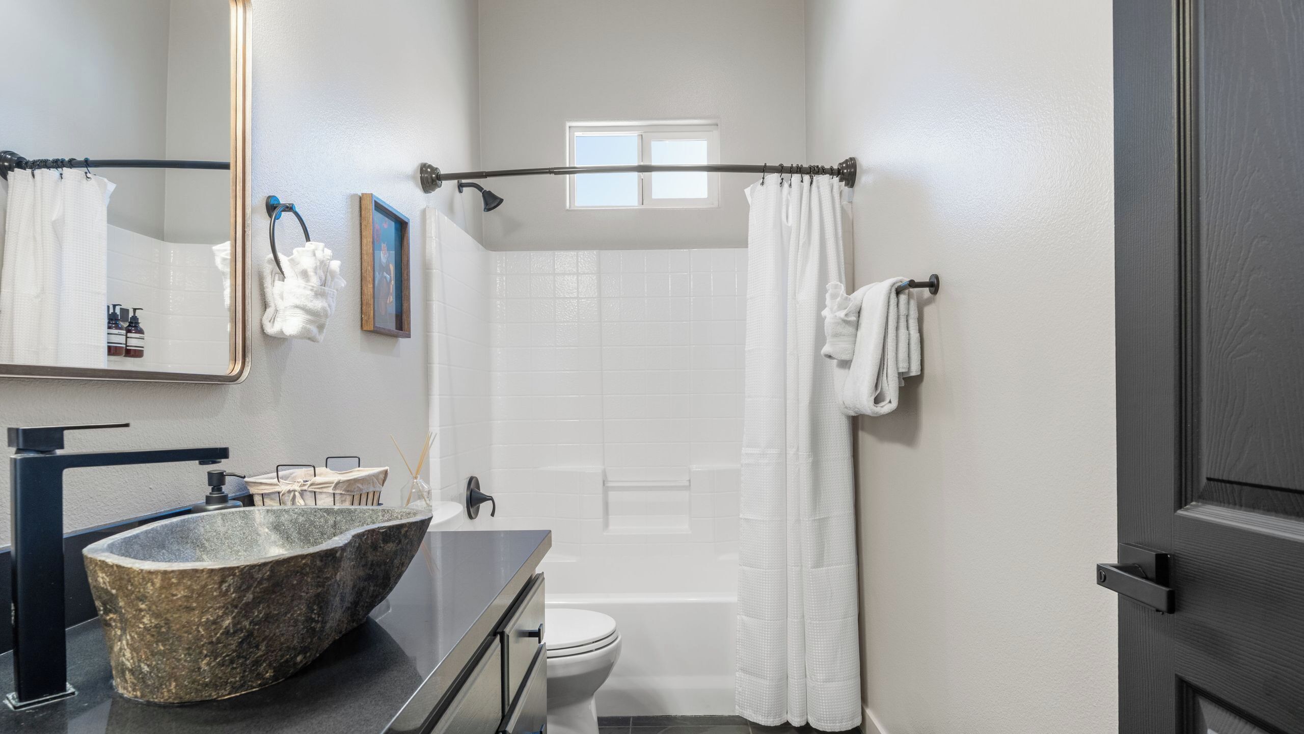 A bathroom with a stone sink, a toilet, a shower, and a bathtub.