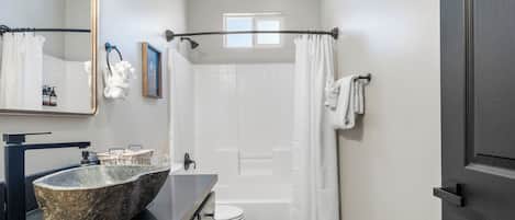 A bathroom with a stone sink, a toilet, a shower, and a bathtub.