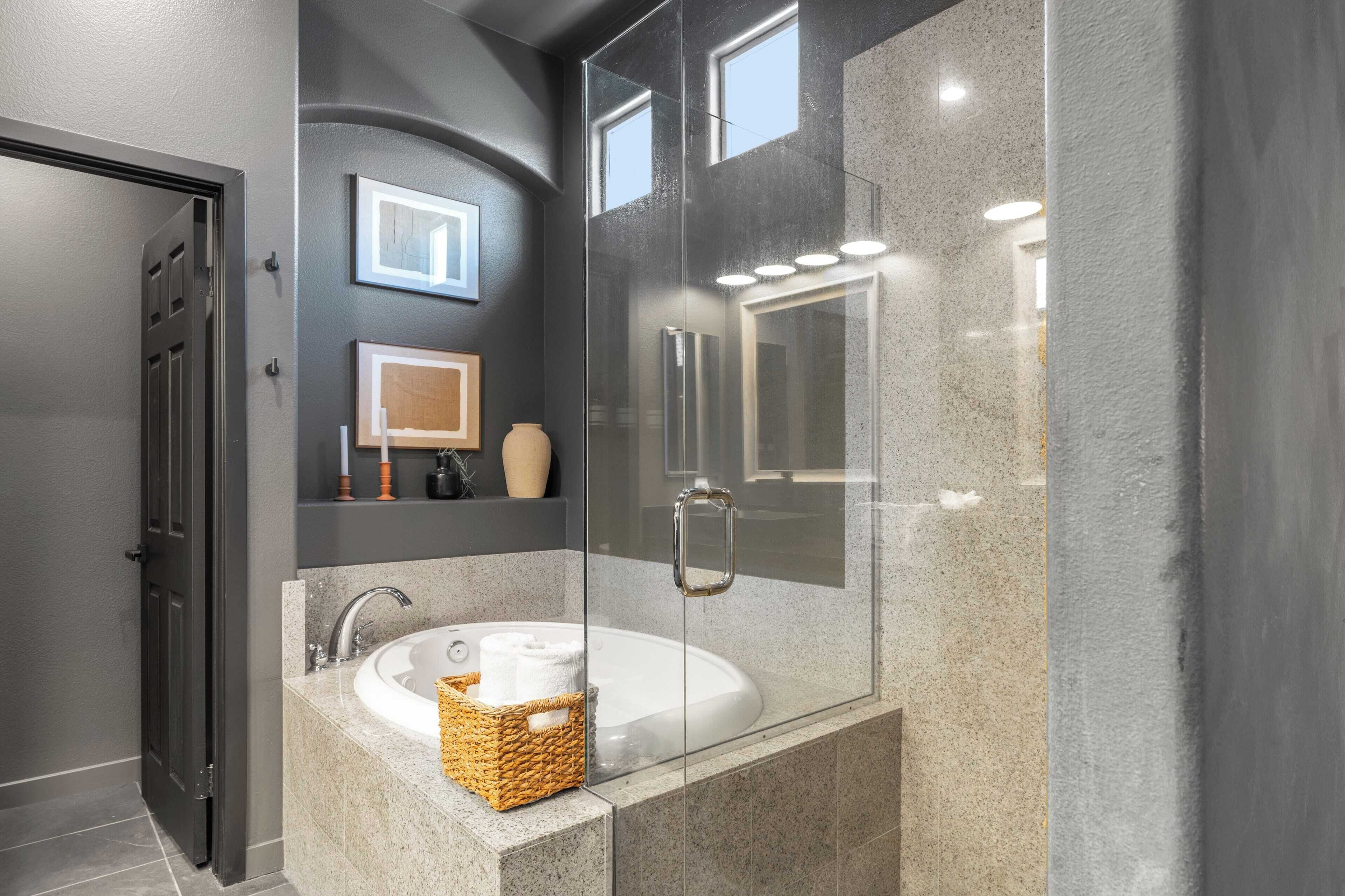 Un baño moderno con ducha envuelta en vidrio, una bañera independiente y un tocador con espejo y perchero.