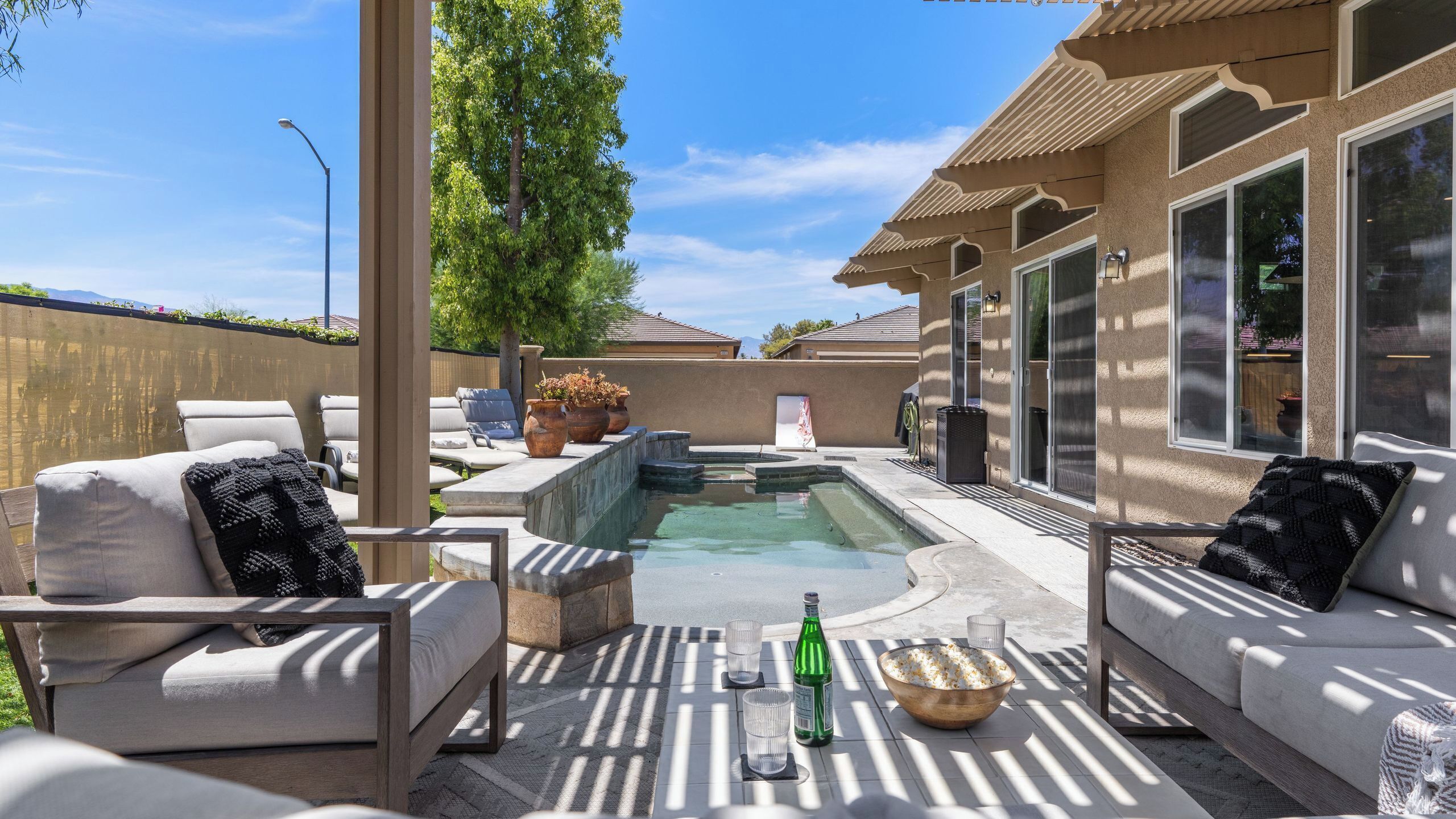 A backyard with a swimming pool, lounge chairs, and a hot tub.