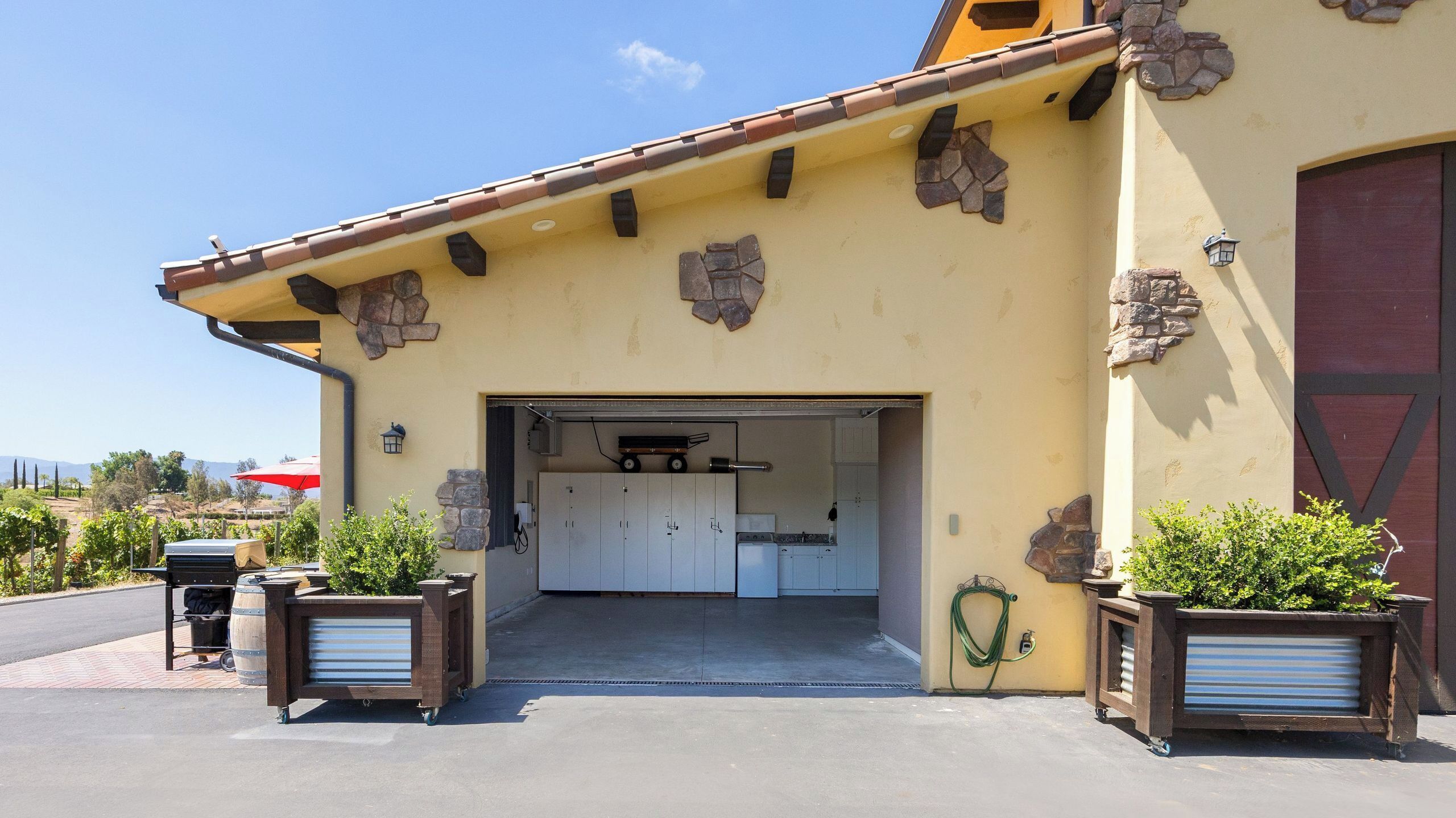 En bygning med garageport, et lille tekøkken og plantekasser.