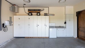 A spacious kitchen with white cabinets, a wooden door, and a countertop with a sink and stove. - New-build Temecula Villa With King Suite, Patio & Vineyard Views The Villa by Avantstay (Temecula)
