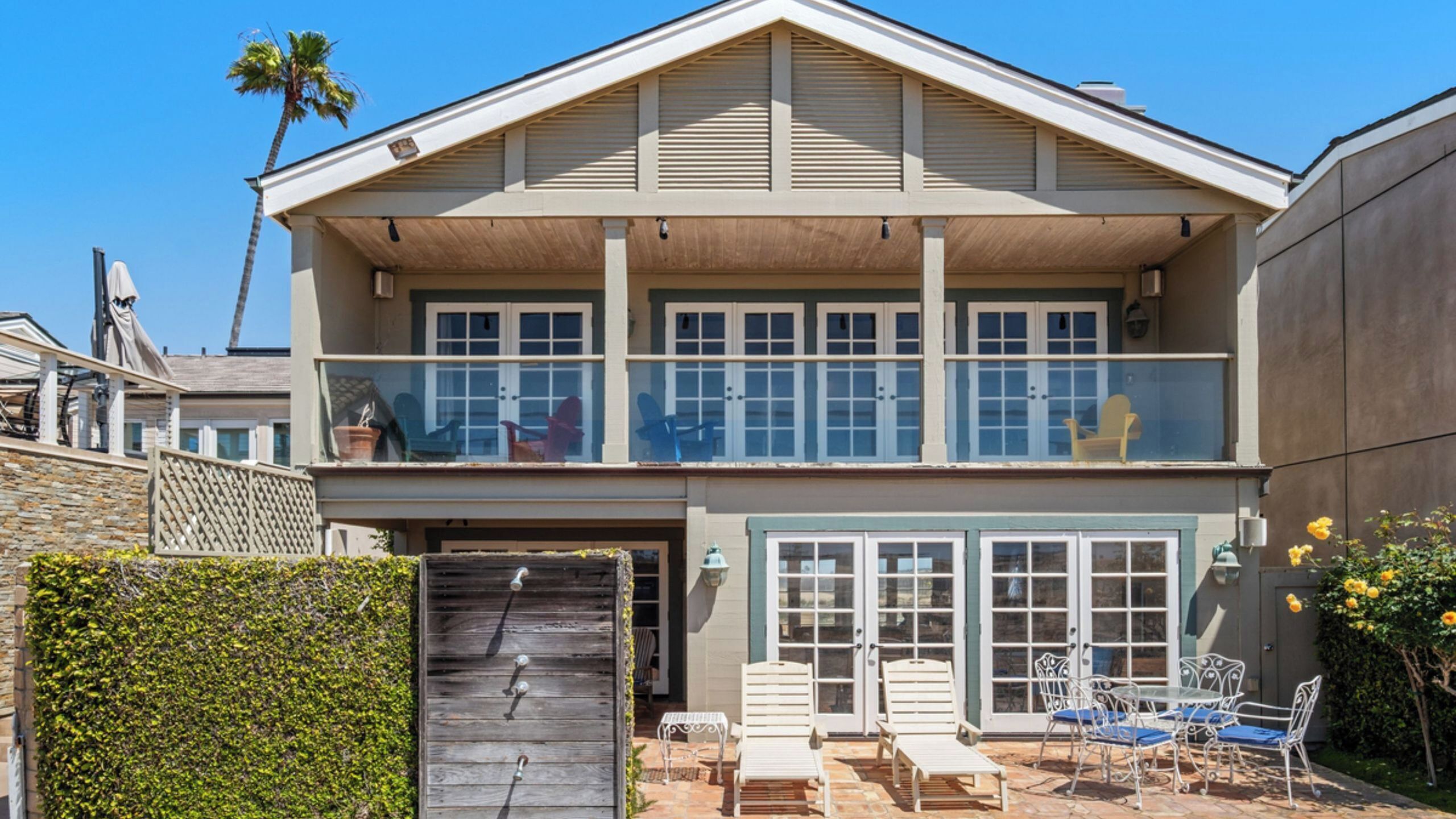A two-story house with a balcony, a garage, and outdoor seating.