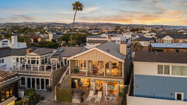 A residential area with houses, a prominent palm tree, and a distant view of a cityscape. - Oceanfront Home Walk to Balboa Pier + Scenic Views Balboa Peninsula Point by Avantstay (Newport Beach)