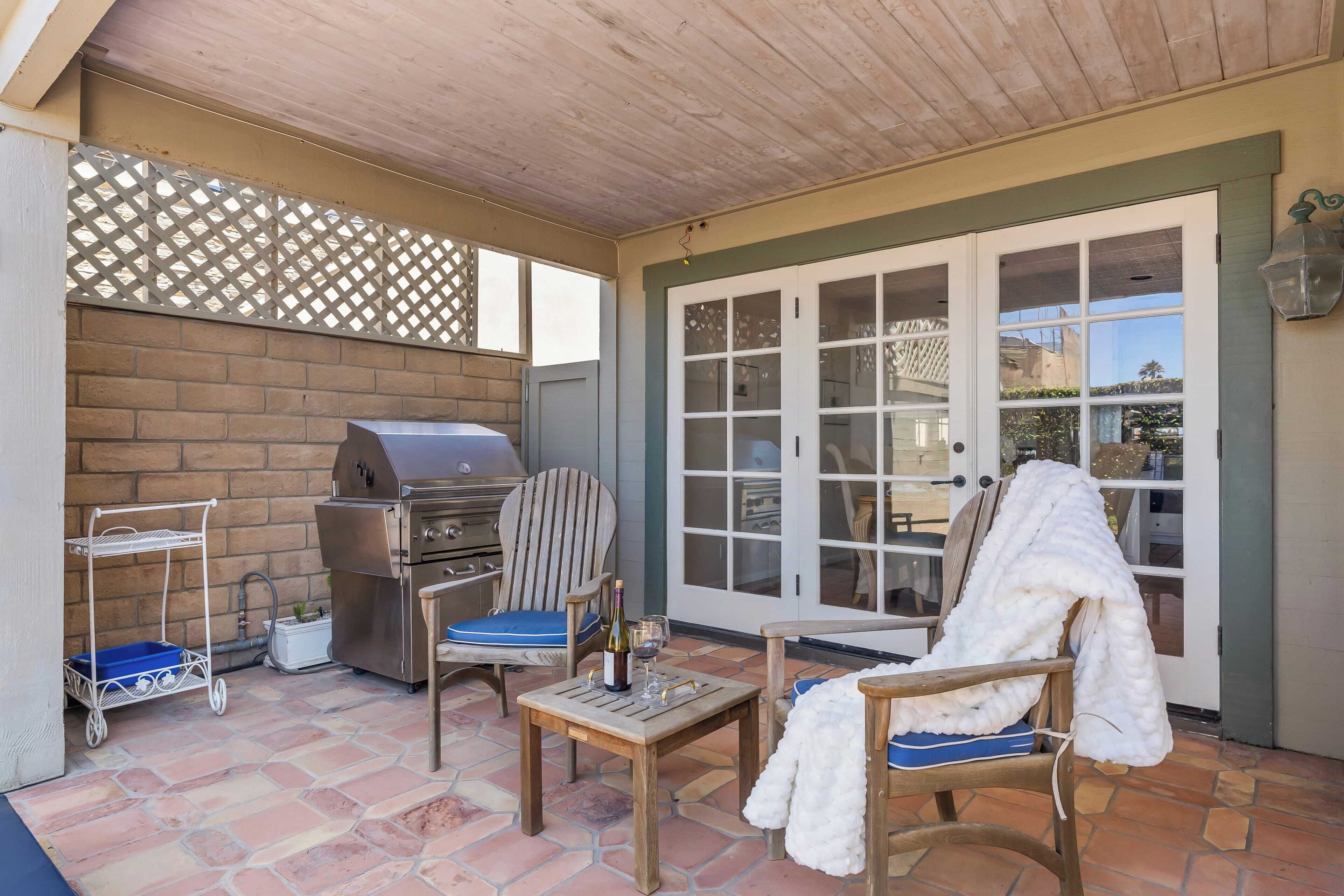 Un espace extérieur aménagé en patio, avec un barbecue, des sièges et une entrée couverte.