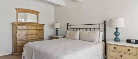 A bedroom with a bed, nightstands, a dresser, and a mirror.