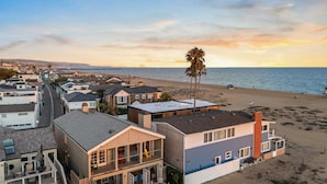 A beachfront property with multiple buildings, a patio area, and a view of the ocean. - Oceanfront Home Walk to Balboa Pier + Scenic Views Balboa Peninsula Point by Avantstay (Newport Beach)