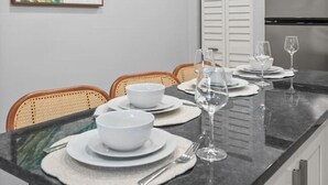 A modern kitchen with white cabinets, a stainless steel refrigerator, and a dining area set with white plates, bowls, and wine glasses. - Cozy Orlando home close to parks, dining, and downtown fun (Orlando)