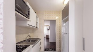 A narrow kitchen with white cabinets, a built-in microwave, and a stainless steel sink. - Apt in BC Center w Balcony 260m From Beach Elo0207 (Balneário Camboriú)