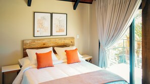 A bed with white and orange pillows, a wooden headboard, and two framed botanical illustrations on the wall. - Pousada Caminho das Araucárias (Urubici)