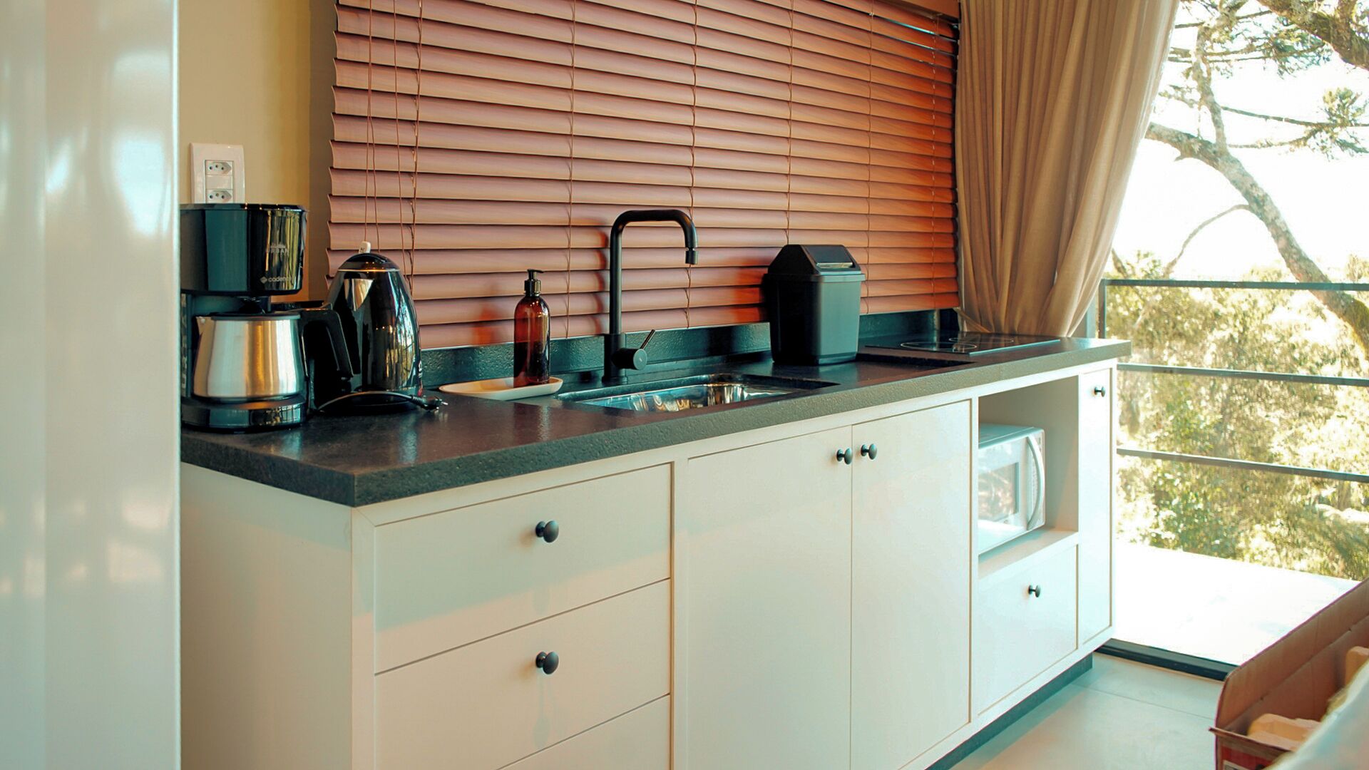 A modern kitchen with a built-in stove, a coffee maker, and a kettle.