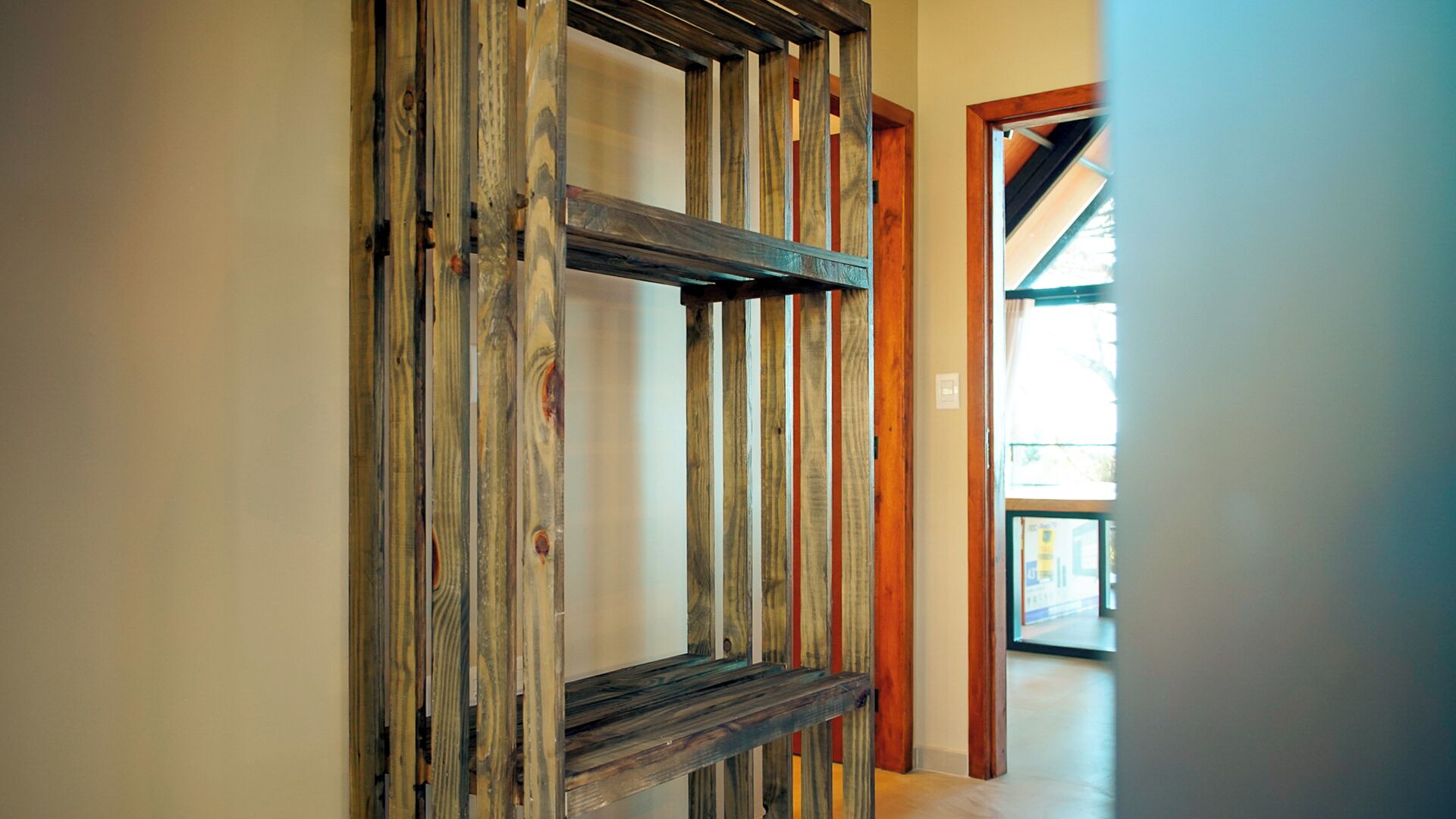 A hallway with a wooden slat partition and a door leading to another room.