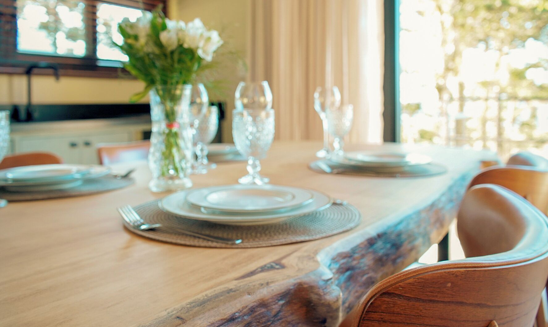 A dining table set with plates, cutlery, and glassware, with chairs around it.