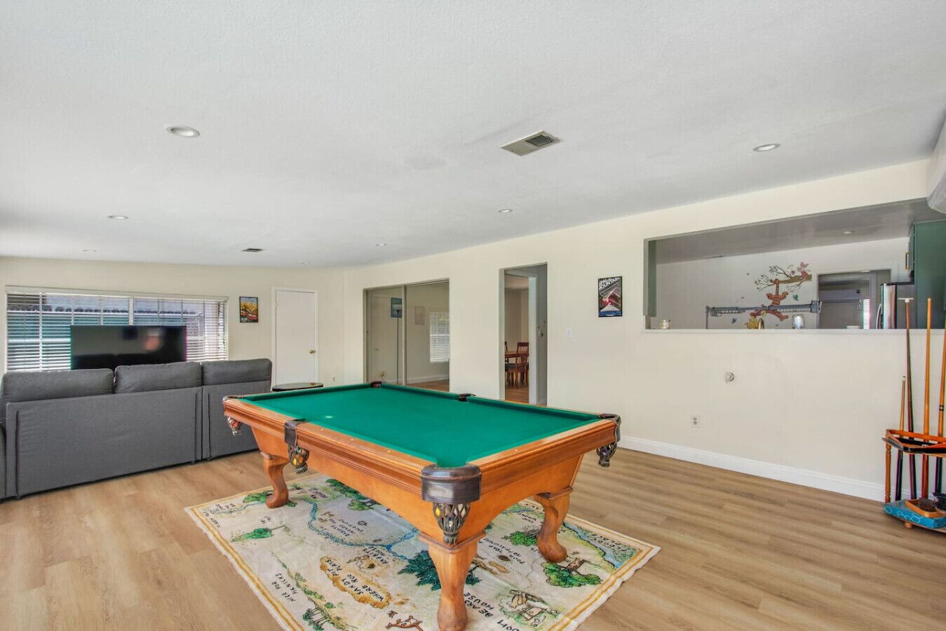 A spacious living room with a pool table, a sofa, and a dining area.