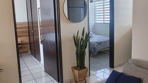Ein modernes Wohnzimmer mit einer Couch, einer Topfpflanze und einem Spiegel an der Wand.
