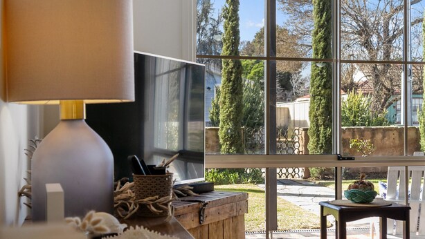 A room with a large window, a television on a wooden table, and a lamp. - Jacks Corner - Moments to the beach, free wifi, pet friendly - wont be disapointed! (Normanville)