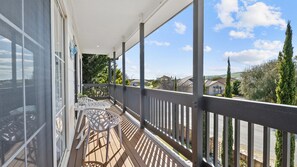 Ein Balkon mit Blick auf eine Wohngegend, einem weißen Geländer und einem Tisch mit Stühlen.