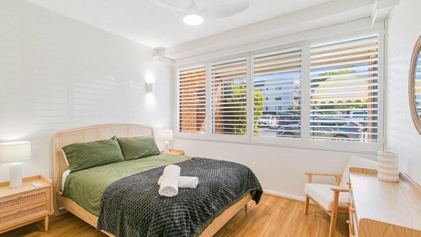 A bedroom with a bed, bedside tables, a desk, and a window with blinds. - Blue Pacific 2 - Beachside Tugun Unit - Linen Provided - Min. 3 Nights! (Tugun)