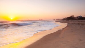 A beach with waves at sunset, a clear sky, and distant buildings. - Blue Pacific 2 - Beachside Tugun Unit - Linen Provided - Min. 3 Nights! (Tugun)