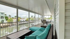 Un espacio al aire libre techado con una terraza de madera, un sofá color turquesa y una mesa con sillas.