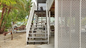 Una escalera que lleva a un edificio con un enrejado blanco.