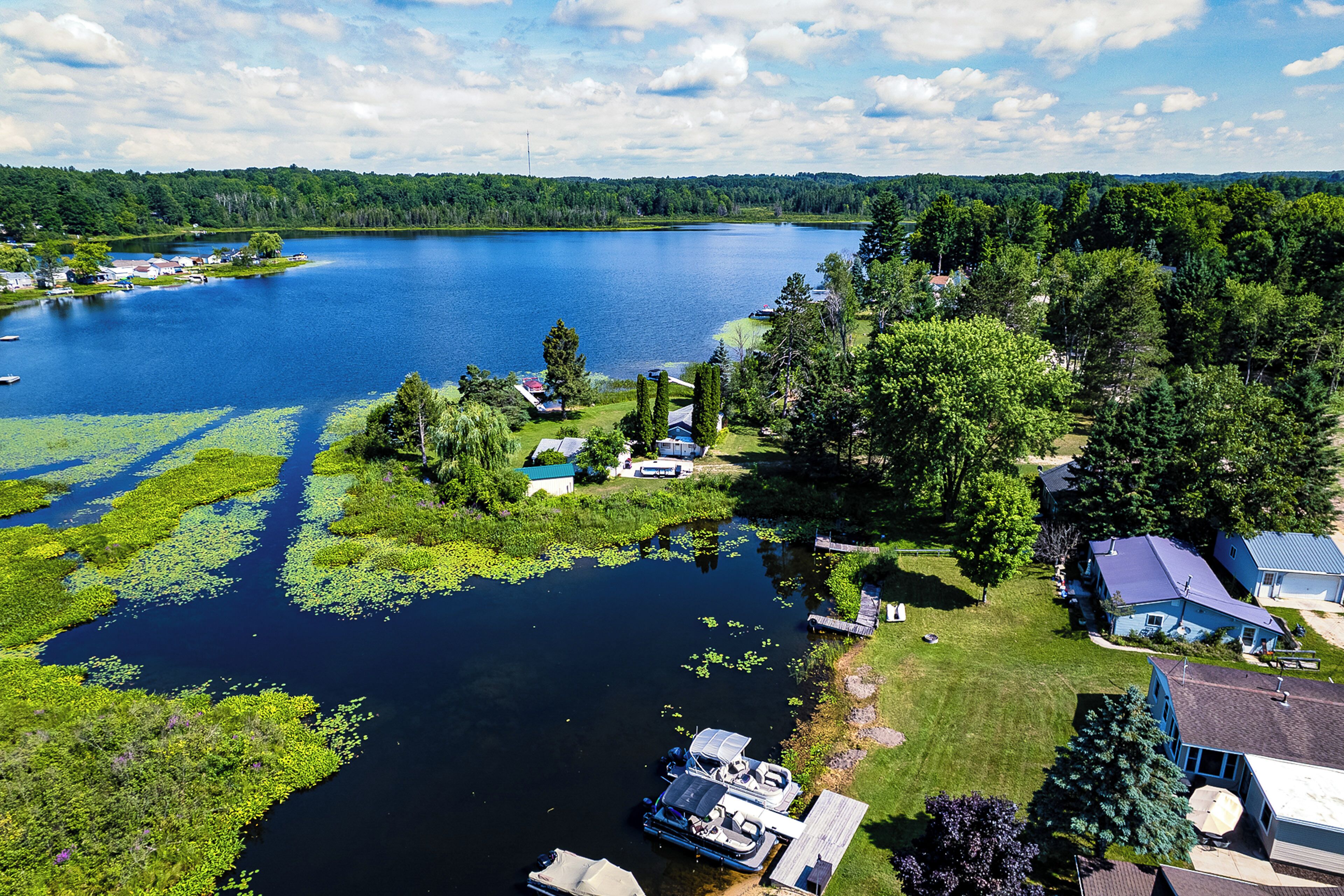A lakeside property with boats docked, a small dock, and a house with a blue roof.