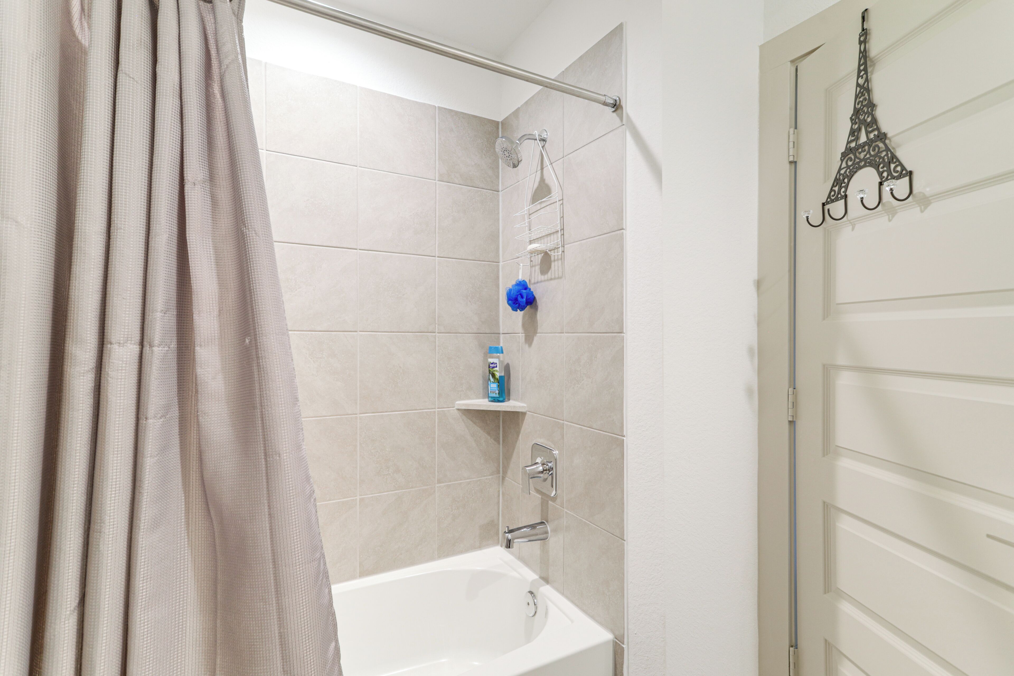 Une salle de bain équipée d’une baignoire, d’une douche et d’une porte agrémentée d’un porte-serviette décoratif.