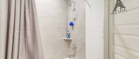 Une salle de bain équipée d’une baignoire, d’une douche et d’une porte agrémentée d’un porte-serviette décoratif.
