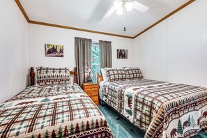 Ein Schlafzimmer mit zwei Betten, einem Holzkopfteil, einem Nachttisch und einem Deckenventilator.