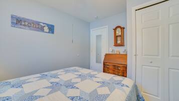 A bedroom with a bed, a dresser, a clock, and a wall sign.