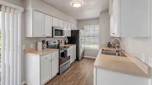 Una cocina moderna con armarios blancos, electrodomésticos de acero inoxidable y una encimera de madera.