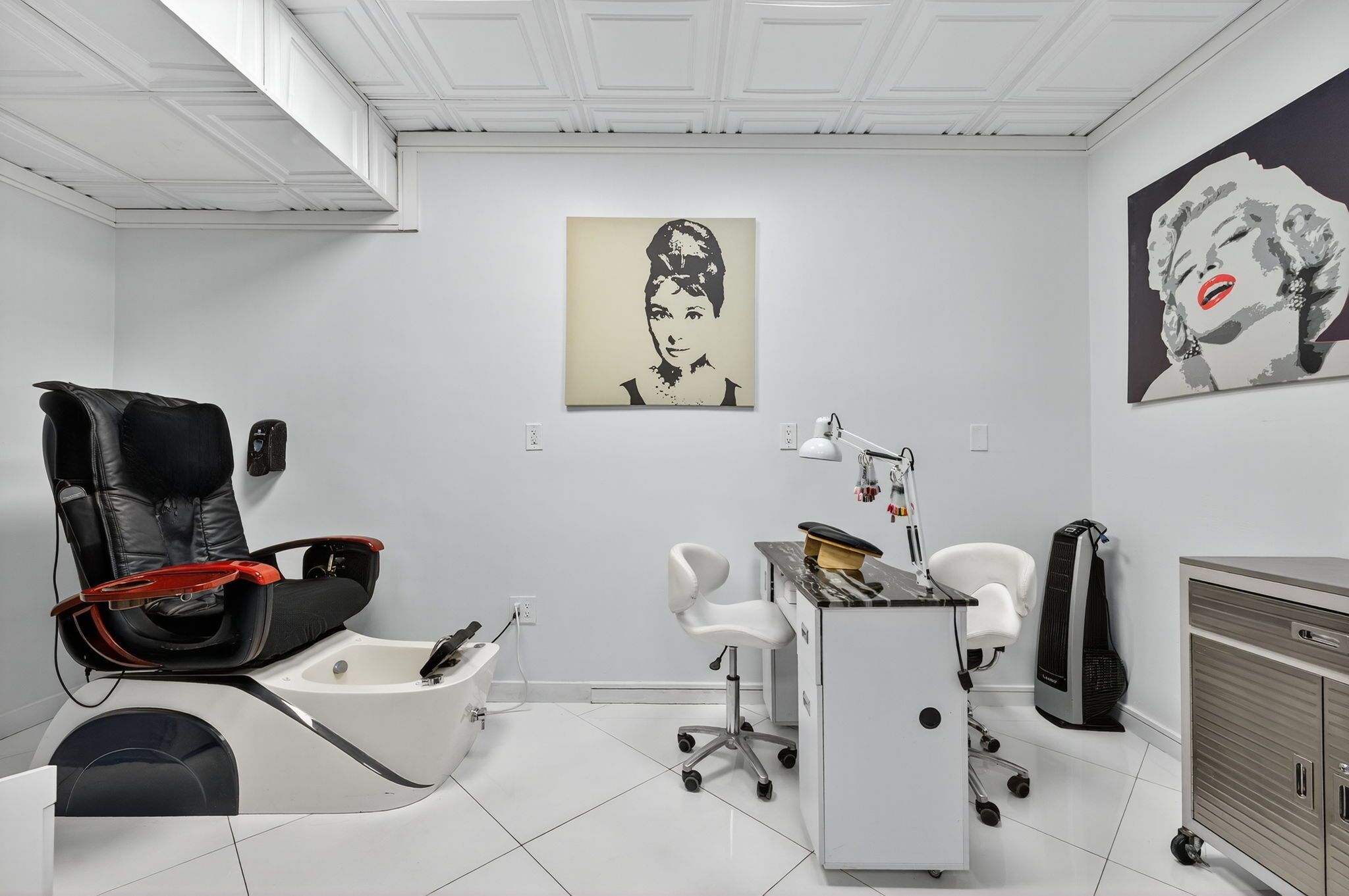 Una habitación moderna y luminosa con una butaca de cuero negro, un escritorio blanco y un armario.
