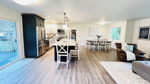 A spacious kitchen with modern appliances, a dining area with a large table and chairs, and a cozy living room with a brown leather sofa. - Luxury 3BR Home + Game Room - Wooded Escape Near Downtown Redmond (Redmond)