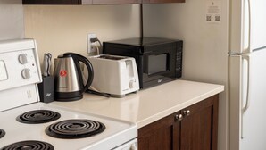 A kitchen with a stove, toaster, kettle, and microwave.