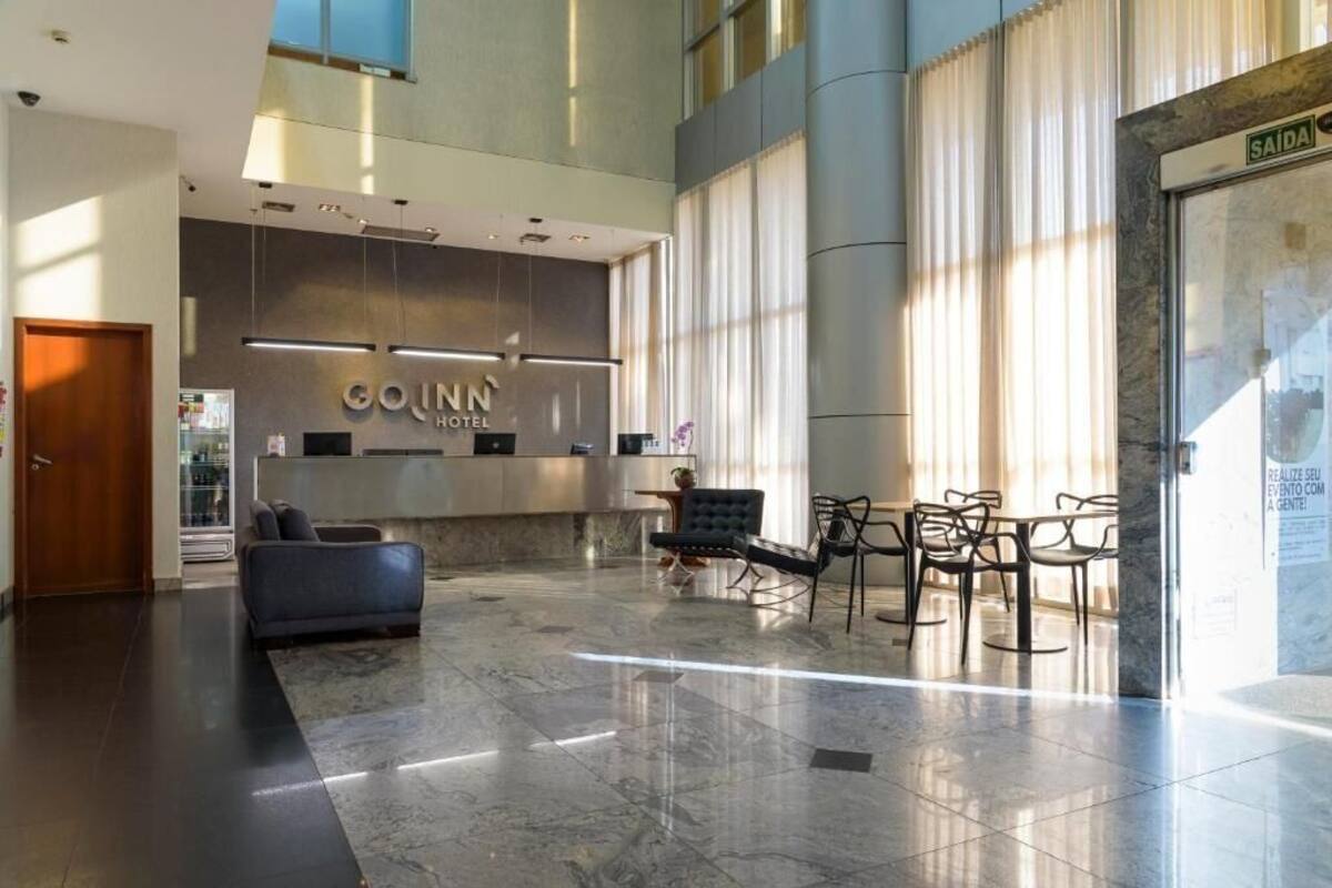 A modern hotel lobby with a reception desk, seating area, and large windows.
