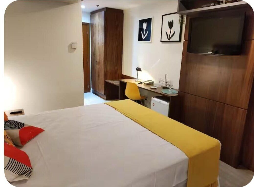 A hotel room with a bed, a desk, a chair, and a TV.