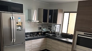A modern kitchen with stainless steel appliances, wooden cabinets, and a black countertop. - Make yourself at home (Goiania)