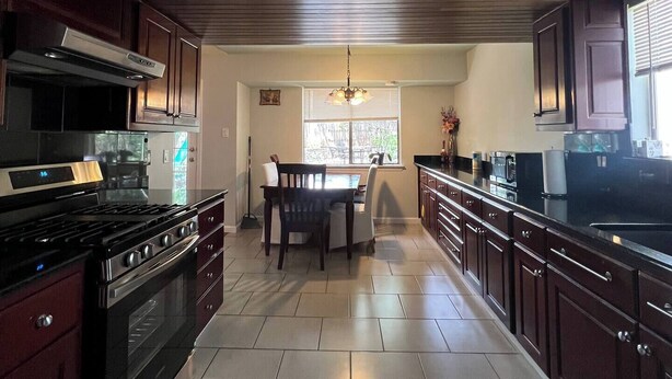 A kitchen with dark wood cabinets, a black stove, and a tiled floor.