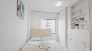Ein ordentlich eingerichtetes Schlafzimmer mit Bett, Nachttisch, Kleiderschrank und Fenster.