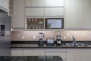 Una cucina moderna con frigorifero, microonde, tostapane, frullatore e macchina del caffè.