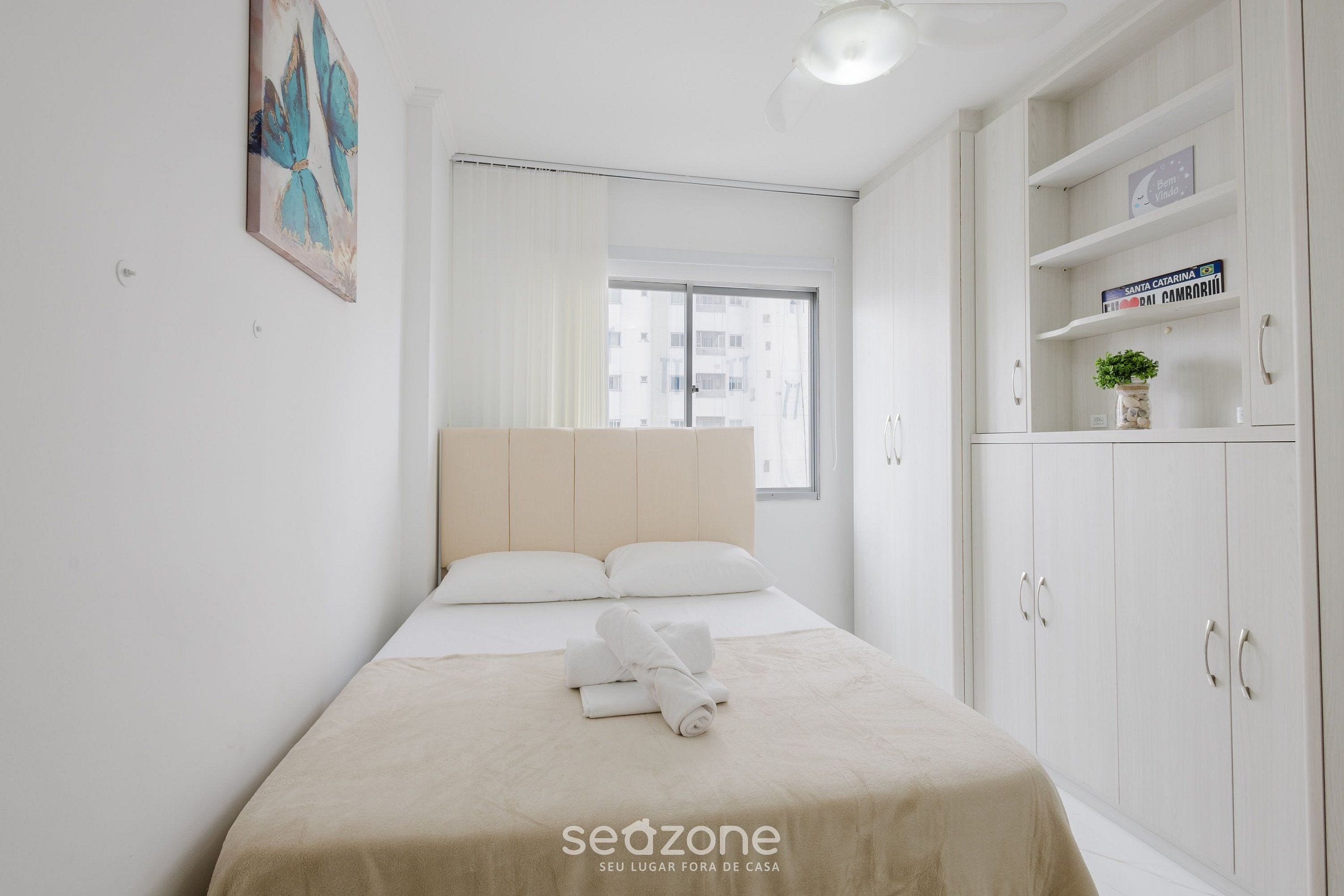 A neatly arranged bedroom with a bed, a bedside table, a wardrobe, and a window.
