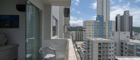 Un apartamento moderno con balcón, ventanas amplias y vistas de edificios circundantes.