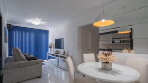 Ein modernes Wohnzimmer mit Sofa, Esstisch mit Stühlen und einem durchgehenden offenen Durchgang zum Küchenbereich.