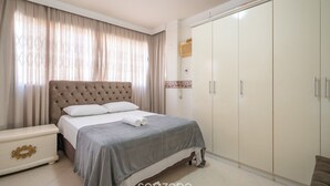 Une chambre avec un grand lit, une armoire et une table de chevet.