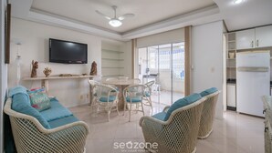 Un vaste espace de vie agrémenté de meubles en osier, d’un téléviseur à écran plat et d’une table à manger.