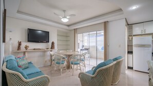 Un vaste espace de vie agrémenté de meubles en osier, d’un téléviseur à écran plat et d’une table à manger.